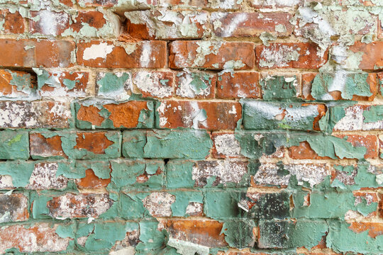 Close up view of rustic brick wall with peeling green paint.