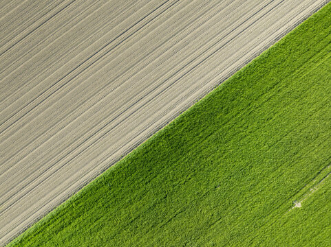 Aerial view of agricultural fields with a diagonal split between plowed soil and vibrant green crops Donaustauf, Bavaria, Germany.
