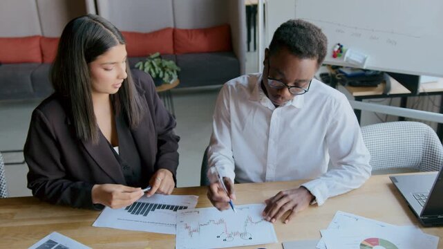 Learning to analyze trading charts in an office with a girl from India and a black guy, focusing on data patterns and market trends while discussing together