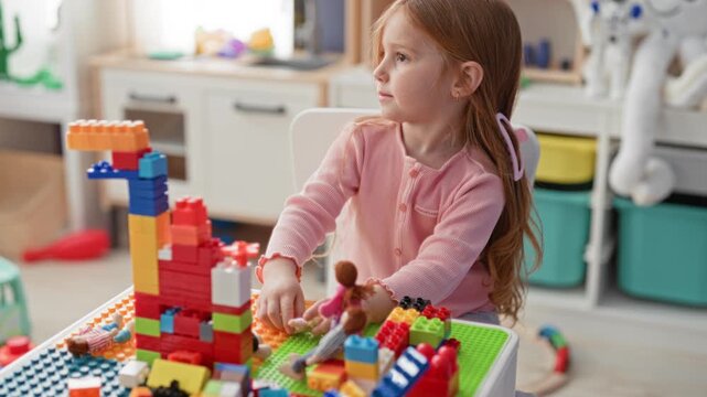 Two little girls stacking colorful plastic blocks and moving a doll with hands on a play table in a building; curiosity and imagination.