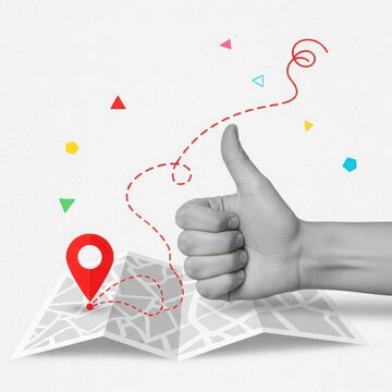 Hand giving thumbs up gesture over folded map with location pin and dashed route line, concept of successful navigation or good review