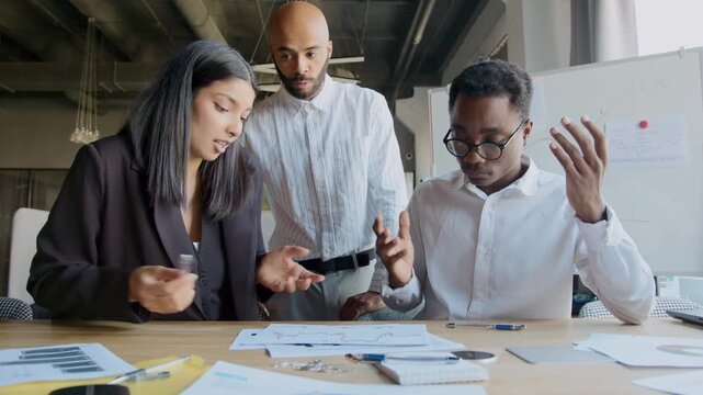 Male boss scolds his colleagues for their mistakes while two employees hold their heads from lack of understanding of how to solve problem and stress they have accumulated.