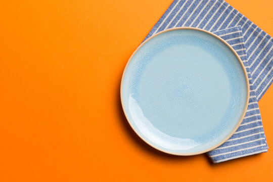 Top view on colored background empty round blue plate on tablecloth for food. Empty dish on napkin with space for your design