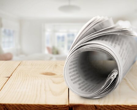 Fresh newspaper rolled up on wooden desk