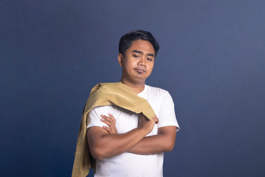 Indonesian civil servant man sighing in relief with hand on chest and closed eyes, jacket on shoulder