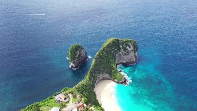 Aerial view of Kelingking sandy beach in tropical island Bali. Green cliff and deep blue ocean waves. Nusa Penida.