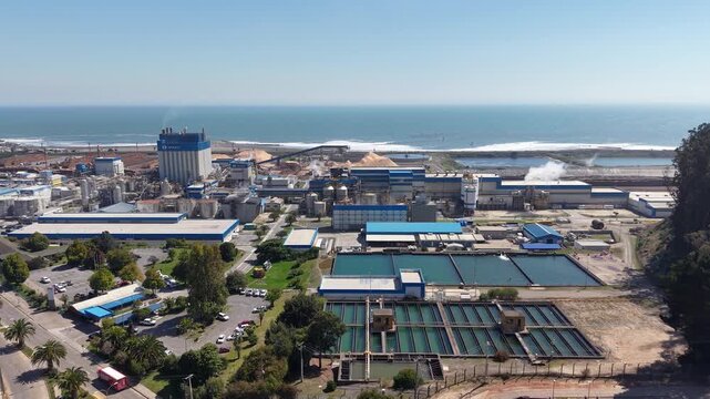 Aerial drone panning shot revealing water treatment pools and Arauco pulp mill in Constitucion, Chile.