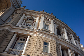 Obraz premium Elegant curved architectural theater facade with columns and windows. Detailed stonework against clear blue sky