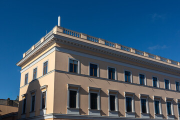 Fototapeta premium Beige building with ornate tall windows under blue sky. European city architectural details