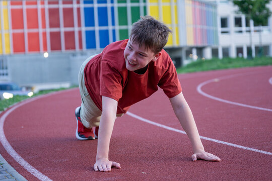 young man doing plank exercise background running track close up teen boy push ups workout athletic stadium concept of sport healthy lifestyle physical activity youth training
