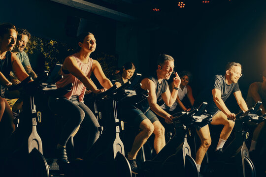 Group indoor cycling spin class with diverse adults pushing through an intense studio workout