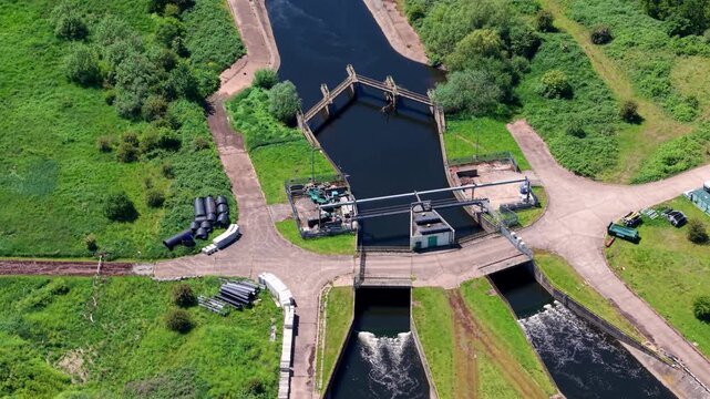 High angle aerial drone view of a scenic forked canal junction for narrowboats surrounded by blue leisure lakes and a green rural landscape in Kingsbury Warwickshire UK