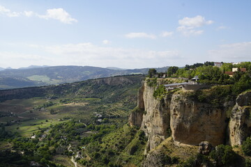 Fototapeta premium This photograph captures the dramatic cliffs and landscape surrounding the historic town of Ronda, located in the Andalusia region of southern Spain. The main landmark is the El Tajo Gorge