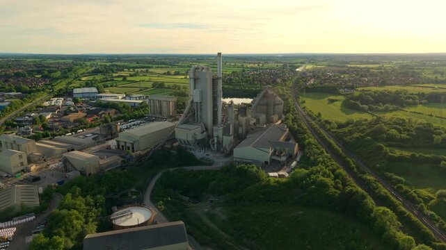 Drone shot of Rugby Cement Plant industrial manufacturing facility and tall exhaust stacks during a vibrant sunset in England
