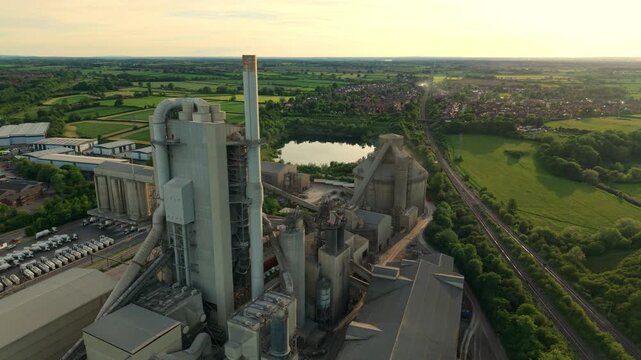 Drone shot of Rugby Cement Plant industrial manufacturing facility and tall exhaust stacks during a vibrant sunset in England