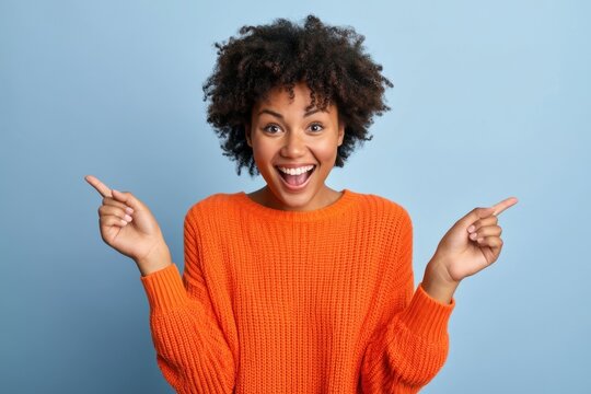 The excited young woman pointing both directions with joyful expression on blue background