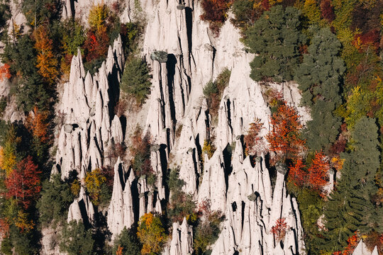 Aerial view of the Piramidi di Terra di Longomoso earth pyramids surrounded by colorful autumn trees in Ritten, Trentino-Alto Adige, Italy.