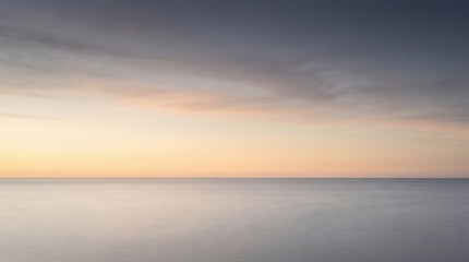Fototapeta premium Tranquil sea at dusk with smooth horizon and warm sky