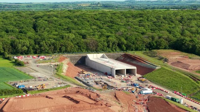High angle aerial view of a major high speed railway twin bore tunnel entrance surrounded by dense green woodland in Warwickshire