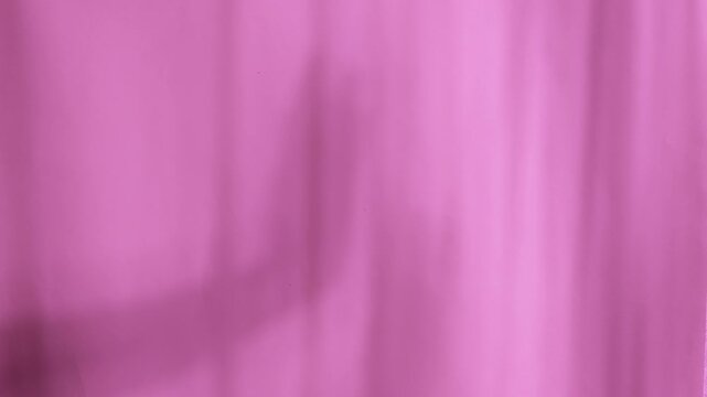 Silhouette of hands moving in graceful dance behind fabric curtain indoors. Mysterious human body shape performing elegant motion through textile material.