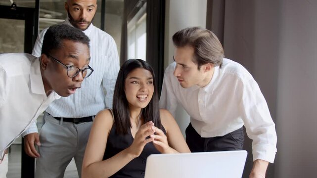 Colleagues celebrate success and victory while watching a laptop in the office, sharing high fives and excitement during a trading achievement