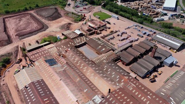 High angle aerial drone view of a massive industrial brick factory and open cast red clay quarry pit for construction manufacturing near Tamworth UK
