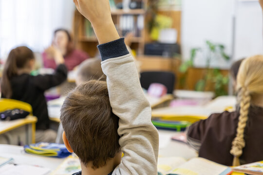 Schoolchild raising hand to answer question in primary school classroom, fostering engagement, active learning, curiosity, and participation among students during a lesson