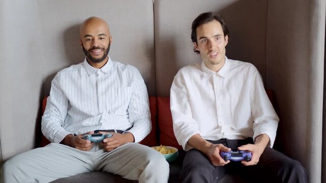 Two friends escape the office chaos, enjoying a fun console gaming session while bonding over laughter and friendly competition during their well-deserved break