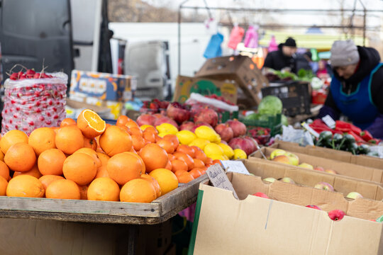 Fresh oranges and assorted seasonal fruits displayed on wooden crates at a local outdoor farmers market, highlighting healthy food choice, organic produce and small business retail