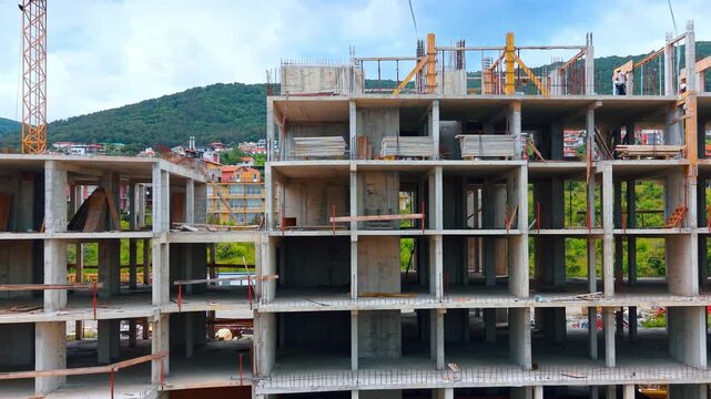 Monolithic concrete frame structure of multi story residential building. Front view of unfinished reinforced concrete building skeleton with formwork materials