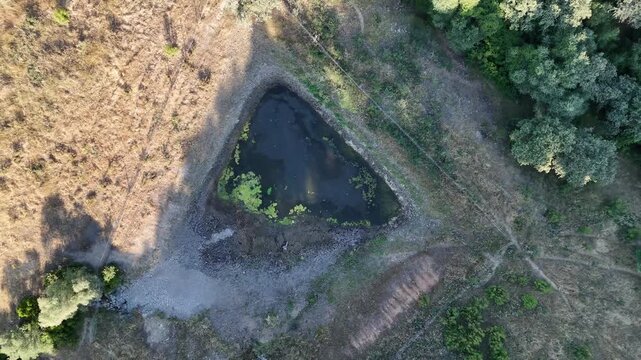 4K Aerial top-down view rising and rotating over a rural agricultural water reservoir during drought