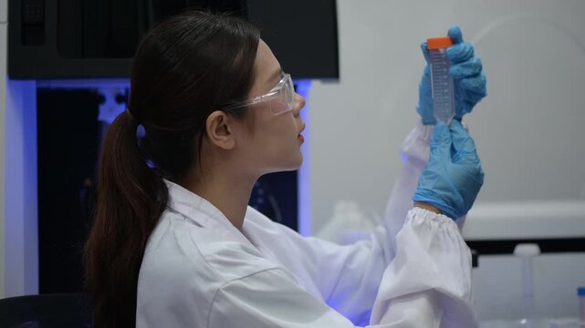 Asian female scientist in white lab coat intently conducting research and analyzing samples to develop vaccine for infectious disease in modern laboratory