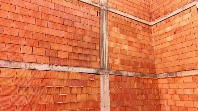 Close up of orange ceramic brick wall with concrete frame. Close-up of a building wall made of orange clay blocks held by concrete pillars and beams.