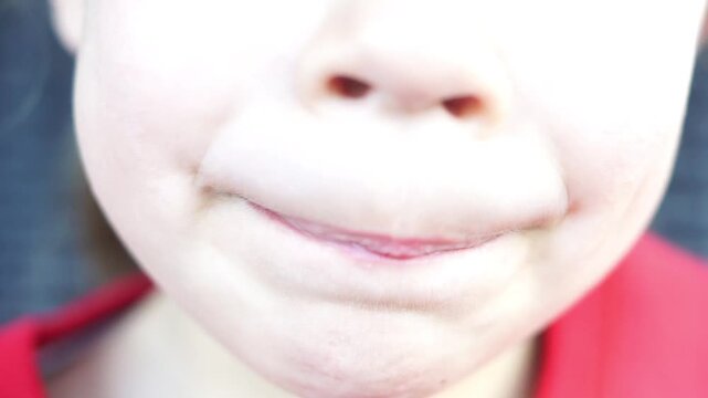 A close-up shot of a cheerful kid opening his mouth wide and smiling brightly, proudly showing his newly lost front teeth and growing permanent ones.