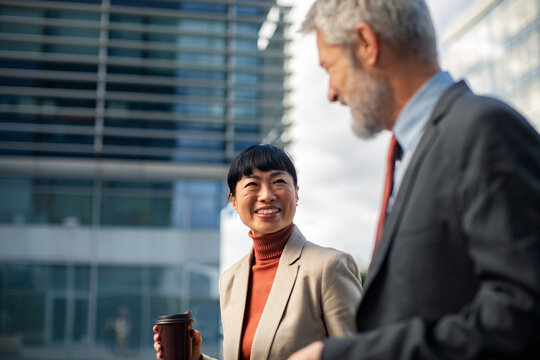 Business colleagues chatting with coffee outside modern office