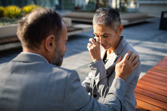 Mature coworkers consoling upset colleague on office terrace