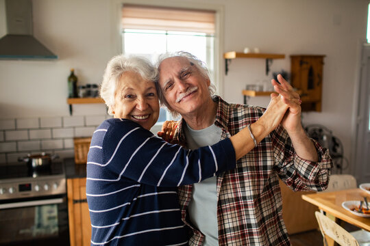 Senior couple dancing and hugging in cozy home kitchen
