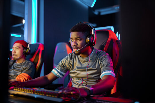Two gamers playing esports at computer stations in neon arena