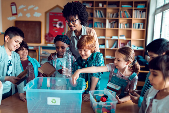 Teacher guiding elementary students recycling in a classroom