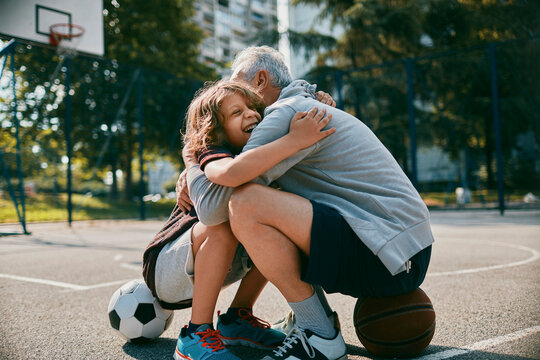 Father and child hugging on outdoor basketball court