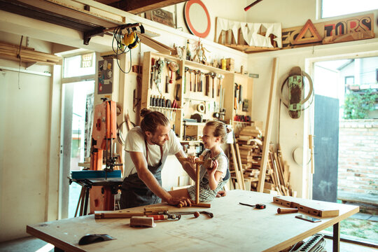 Father teaching daughter woodworking in home workshop
