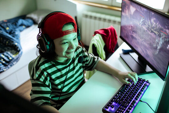 Teen wearing headset playing pc game at home