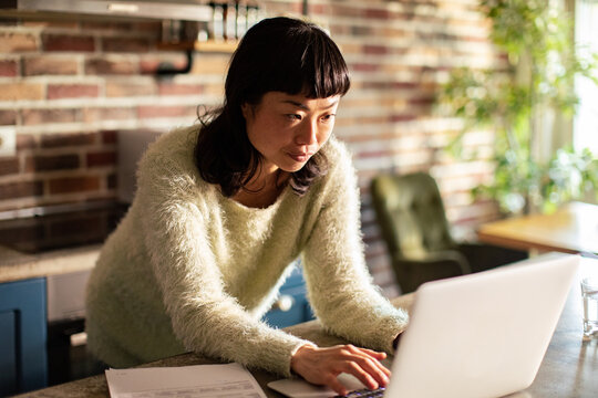 Focused woman working on laptop in a home kitchen