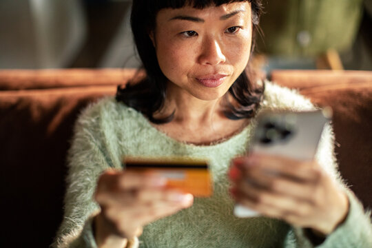 Woman using credit card and smartphone at home