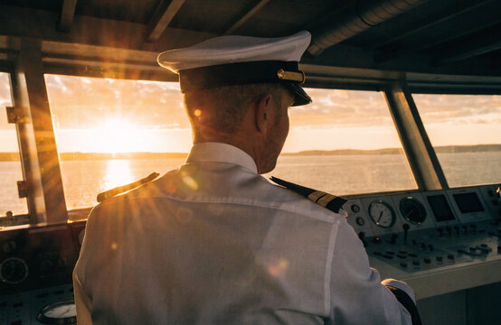 Ship Captain Standing on Wheelhouse Bridge Overlooking Sunset Sea Navigation and Maritime Control