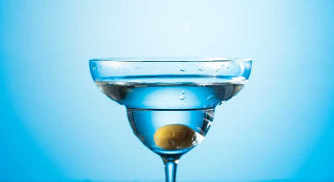 Clear martini glass with green olive.