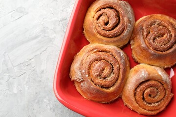 Fototapeta premium Delicious cinnamon rolls in baking dish on grey textured table, top view. Space for text