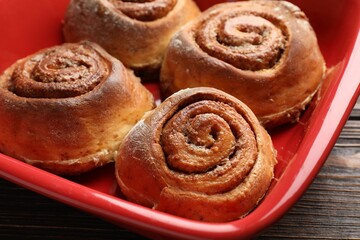 Fototapeta premium Delicious cinnamon rolls in baking dish on wooden table, closeup