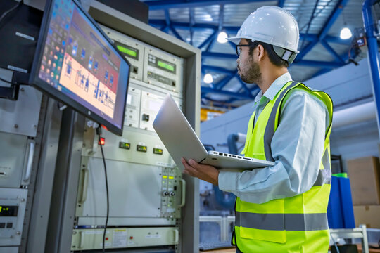 Professional engineer monitoring industrial automation system on digital screen in high-tech factory control room. Concept of smart manufacturing, technical data analysis, and modern engineering.