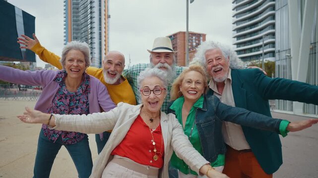 Cheerful group of elderly friends smiling and celebrating life together in a modern city setting. Stylish retired people enjoying their free time, laughing, and looking at the camera